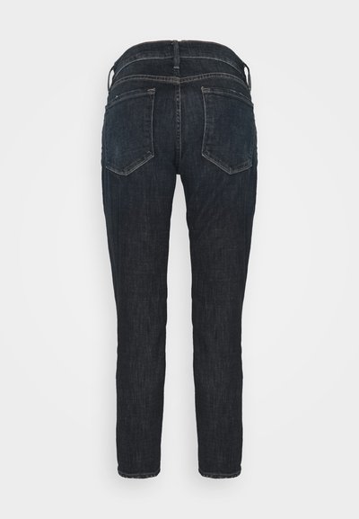 Jeans skinny in denim blu scuro con vita media, cuciture visibili, due tasche posteriori e una texture liscia.