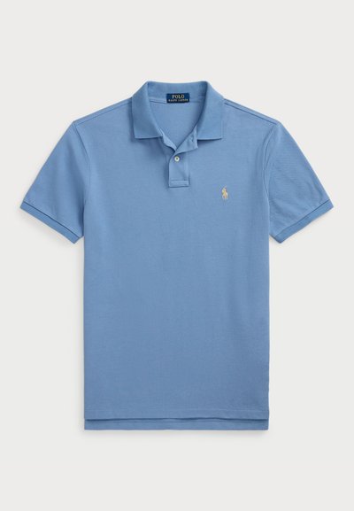 Polo azul claro de algodón con cuello clásico y tapeta de dos botones, con un pequeño logotipo bordado en amarillo en el lado izquierdo del pecho.