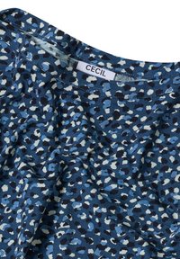 Blau gemusteter Stoff mit einer Mischung aus dunklem und hellem Blau, weißen und schwarzen Punkten; runder Ausschnitt; Etikett mit der Aufschrift "CECIL" sichtbar.