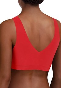 Roter nahtloser BH mit tiefem V-Back-Design. Hergestellt aus weichem, elastischem Material, mit breiten Trägern und glatter Textur.