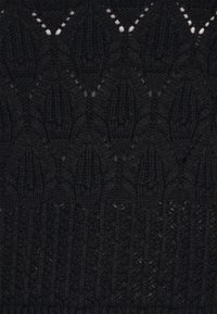 Fekete kötött textil gyémántmintával és apró nyitott szemekkel, az alsó részen bordázott textúrával a részletek kiemelésére.