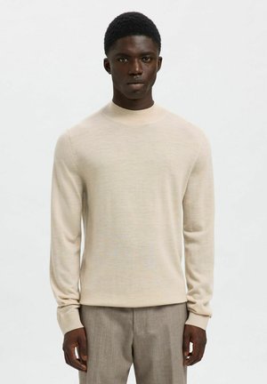 Beige knit sweater with a round neckline and long sleeves, made of soft fabric, featuring a smooth texture and fitted silhouette.