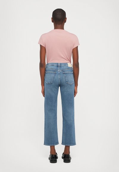 Light pink t-shirt and high-waisted blue jeans with a straight, cropped leg, subtle back pocket stitching, and a label on the waistband.