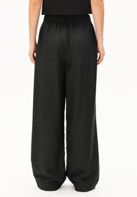 Vida byxor i mörkgrått tyg med elastisk midja. Mjuk textur med ett slätt, skräddarsytt utseende. Minimalistisk design, utan mönster.