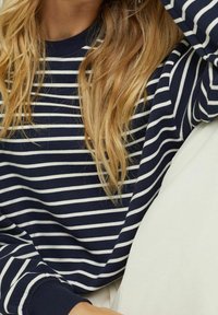 Sweat-shirt à rayures bleu marine et blanc avec un col rond et des manches longues, doté d'un tissu texturé et de poignets côtelés.