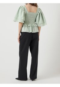 Grönrutigt peplumtop med puffärmar, smockad bodice och fyrkantig ryg. Matchas med svarta vidbyxor.