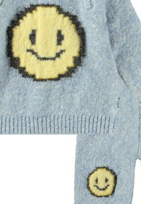 Jasnoniebieski sweter o puszystej fakturze z dużą żółtą uśmiechniętą buźką na przodzie i mniejszą buźką na mankiecie.