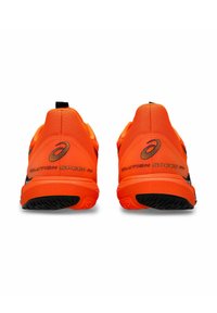 Baskets de sport orange vif avec une tige en mesh texturé, des accents noirs et un talon prononcé. Présente le branding "SOLUTION SPEED FF".