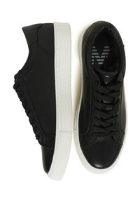 Paire de baskets basses noires avec semelles épaisses blanches et lacets noirs, vues de côté et de dessus sur fond blanc.