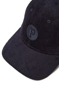 Gorra de béisbol de pana negra con un parche redondo que presenta una "P" en relieve en el panel frontal.