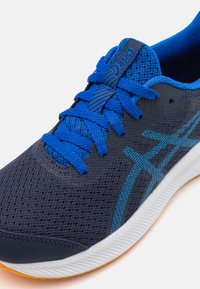 Blue mesh athletic shoe with a dark navy base, contrasting bright blue laces, and an orange outsole; features Asics logo and textured details.