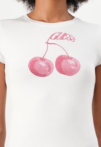 Hvit bomulls t-skjorte med rosa rhinestone-kirsebær og ordet "Gloss" i en buet design over dem. Korte ermer, tettsittende snitt.