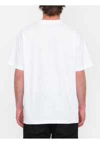 Camiseta de algodón blanca con cuello redondo, mangas cortas y un corte relajado. La parte trasera es sencilla, sin gráficos ni patrones.