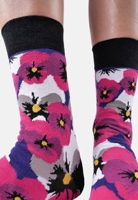 Calcetines de tobillo coloridos con un patrón floral que presenta flores rosas, moradas y negras, y un puño negro acanalado sólido en la parte superior.
