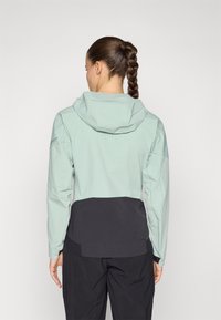 Hellgrüne, wasserdichte Jacke mit Kapuze; verfügt über einen schwarzen unteren Abschnitt, Belüftungslöcher im Rücken und lange Ärmel.
