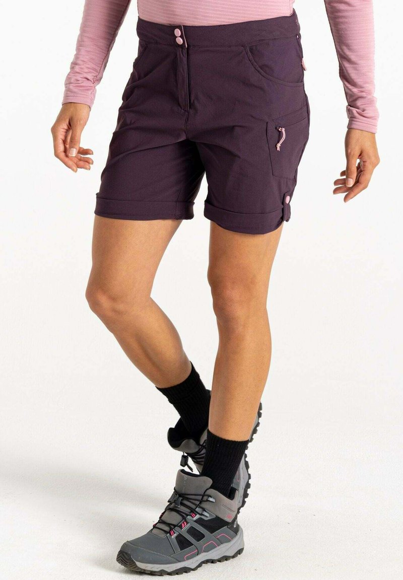 Pantalones cortos morados para exterior con puños enrollados, que cuentan con dos bolsillos frontales, un bolsillo lateral con un zipper rosa, y combinados con botas de senderismo grises.