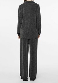 Set da lounge grigio con texture composto da una camicia a maniche lunghe con bottoni e pantaloni a gamba larga, entrambi con un motivo discreto e vestibilità rilassata.