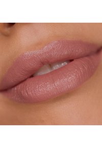 Matowa szminka w ciepłym odcieniu nude, charakteryzująca się gładką teksturą i wyraźnie zarysowanymi ustami z delikatnym połyskiem, podkreślająca naturalny wygląd.