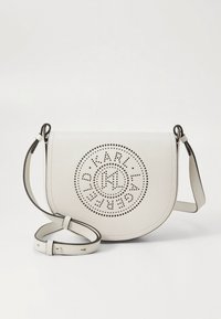 Borsa a tracolla in pelle bianco sporco con design circolare perforato e dettaglio logo, dotata di tracolla regolabile. Texture liscia e forma curva.