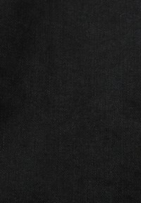 Gros plan d'un tissu denim noir montrant la texture en sergé et le motif de couture en diagonale.