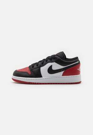 Sneaker basse en cuir noir, rouge et blanc avec des lacets noirs et une semelle intermédiaire blanche, vue de côté sur fond blanc.