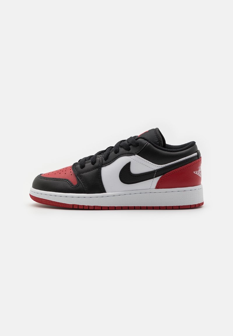Sneaker basse en cuir noir, rouge et blanc avec des lacets noirs et une semelle intermédiaire blanche, vue de côté sur fond blanc.