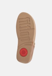 Fleksibel gummisåle med strukturerte mønstre, med en rød sirkelakent og preget logo. Glatte kanter og ergonomisk design.