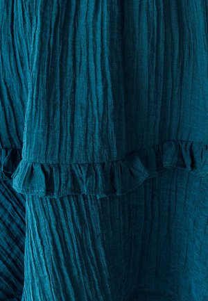 Teal textiel met een gestructureerd oppervlak, voorzien van verticale plooien en een ruffled zoom. Zacht, valt soepel en benadrukt diepte en beweging in het ontwerp.