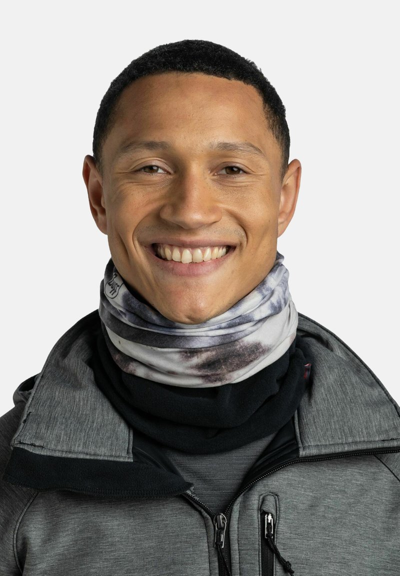 Gaiter de cuello con múltiples patrones en tejido suave; presenta tonos grises y negros con un diseño en espiral. Se lleva debajo del cuello de una chaqueta oscura.