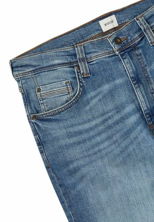 Blaue Jeans aus Denim mit klassischem Fünf-Taschen-Design, auffälliger Waschung, Kupfernähten und Reißverschluss. Das Etikett trägt die Aufschrift "MUSTANG."