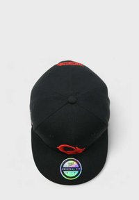 Musta pesäpallohattu, jossa on kaareva lippa, punainen brodeerattu logo, teksturoitu kangas ja holografinen kokolappu etupuolella.