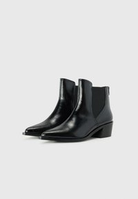 Black ankle boots made of glossy leather with a pointed toe, elastic side panels, and a low block heel. Features a simple design.