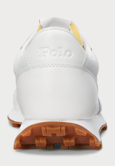 Balti sportiniai bateliai su lygiu odiniu paviršiumi ir kvėpuojančia tinkleliu. Ypatybės: guminis padas su sukibimo pakylomis ir iškilmingu "Polo" logotipu.