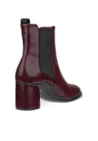 Burgundy läderankelboot med rund tå, svarta elastiska sidopaneler och en kraftig klack. Slät finish med en matt yta.