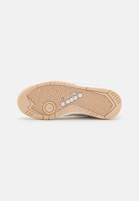 Sole of a sneaker with a textured light brown rubber, featuring a diagonal pattern and a circular emblem with the brand name "diadora."