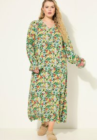 Robe maxi florale avec un motif vert, jaune, rouge et bleu ; manches longues avec des poignets à volants ; design en V ; tissu doux ; longueur jusqu'aux chevilles.