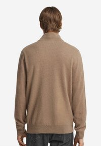 Tansfarbener Strickpullover mit Kragen, weicher Textur und gerippten Bündchen. Einfaches, sauberes Design ohne sichtbare Marken oder Muster.