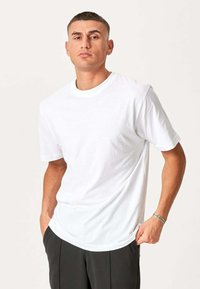 Hvid kortærmet T-shirt lavet af bomuld, med rund hals og afslappet pasform. Glat tekstur uden mønstre eller synlige detaljer.