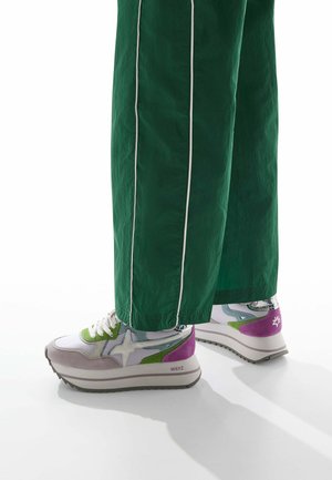 Multicolored sneaker featuring a white base, green, purple, and gray accents, with a textured outsole and distinct star logo.