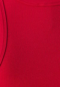 Tissu côtelé rouge avec une texture lisse et un éclat subtil, présentant un col rond et des bords surpiqués.