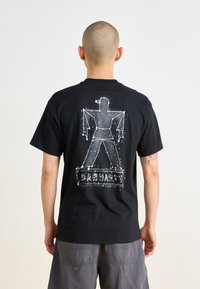 T-shirt de algodão preto com um design gráfico branco de um robô e a palavra "CARHARTT", com mangas curtas e decote redondo.