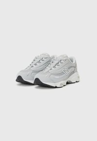 Grå sneakers med en ovandel i mesh och syntetmaterial, rundad tå, snörningssystem och en yttersula i vitt och svart gummi.