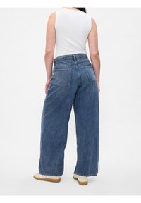 Jeans de pierna ancha de tiro alto en denim azul oscuro, con un acabado suave, cinco bolsillos y cierre de cremallera.