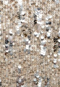 Tissu beige densément recouvert de sequins argentés superposés, créant un motif texturé et réfléchissant de petites formes circulaires.