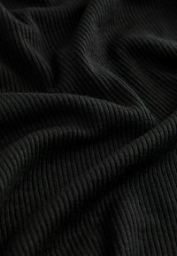 Black ribbed fabric with a soft texture, featuring vertical lines and gentle folds, showcasing its stretchable and comfortable design.
