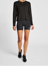 Czarna, długosleeve'owa koszulka sportowa, w zestawie z czarnymi szortami. Szorty mają logo. Oba produkty wykonane są z materiału odprowadzającego wilgoć.