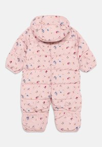 Combinaison de neige rose en duvet avec des motifs floraux en bleu, jaune et rouge. Présente une capuche, des manches courtes et des sections matelassées.