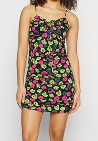 Blumenkleid im Mini-Stil mit schwarzem Hintergrund, das mit rosa und grünen Rosenmuster verziert ist, verstellbaren Spaghettiträgern und einem gerafften Vorderbanddetail.