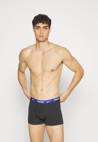 Boxer uomo neri con fascia in vita blu e bianca con logo Nike. Realizzati in tessuto elasticizzato, presentano un design ancorato sul davanti.
