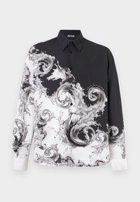 Μακρυμάνικο μαύρο και λευκό πουκάμισο με κουμπιά, με στροβιλιζόμενα μπορντώρα κύματα και γιακά, με ετικέτα Versace Jeans Couture μέσα στο γιακά.